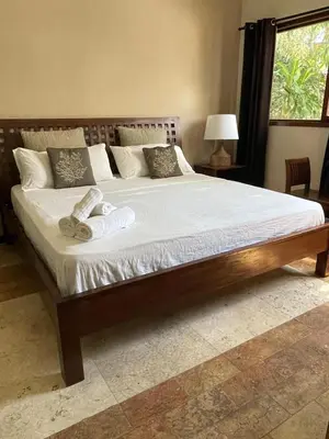 a large bed with a wooden frame in a bedroom at Villa exotic in Juan Dolio