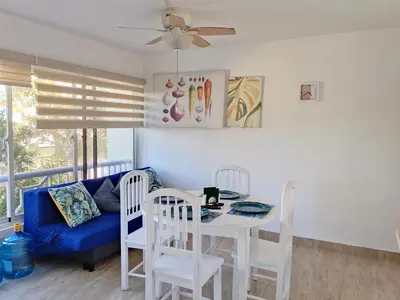 a living room with a table and chairs and a blue couch at Residencias Turísticas Espinosa in Villas del Mar