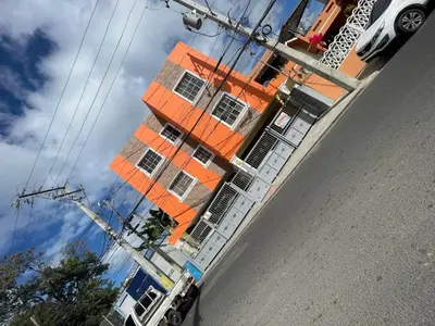 an orange building reflection in the side of a street at Bohio rd in Santo Domingo