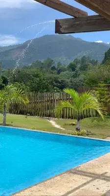 a blue swimming pool with palm trees and a fence at Villa 3 Habitaciones con piscina in Jarabacoa