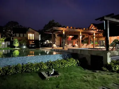 a person sitting on a bench in front of a house at Villa 3 Habitaciones con piscina in Jarabacoa