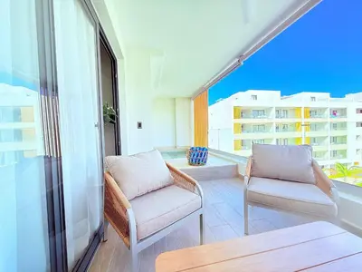 a balcony with two chairs and a view of a building at Gardenia Beachside Living in Punta Cana