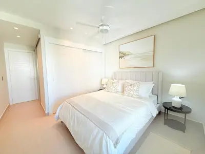 a white bedroom with a bed and a table at Gardenia Beachside Living in Punta Cana