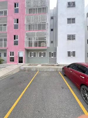 a red car parked in a parking lot in front of buildings at Apartamento en bani in Baní
