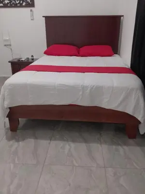 a bed with two red pillows on top of it at Brisa del mar in Boca Chica
