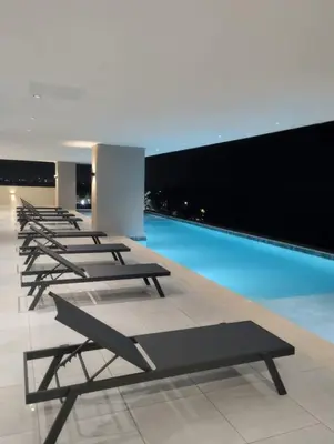 a row of lounge chairs in a building with a pool at Comfortable oceanfront apartment on Av España in La Francia