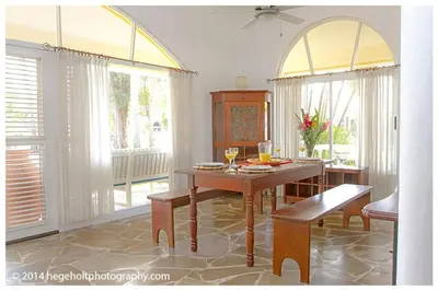 a dining room with a table and two windows at Villa Dawn, Bahia de Arena in Cabarete