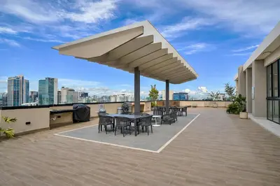 a patio with tables and chairs on the roof of a building at Modern Luxury Apt Pool, Gym and Prime Location in La Julia