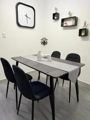 a dining room table with chairs and a clock on the wall at Comfy & Secure Modern 2BR Apartment just 5 minutes from Airport in Boca Chica in Boca Chica