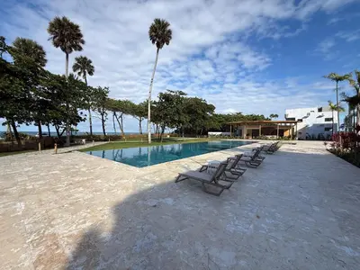 a swimming pool with lounge chairs and palm trees at Stunning oceanfront apartment in Encuentro at The Wave in Cabarete