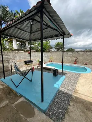 an umbrella over a chair next to a swimming pool at Pequeña villa de María in Villa Mella