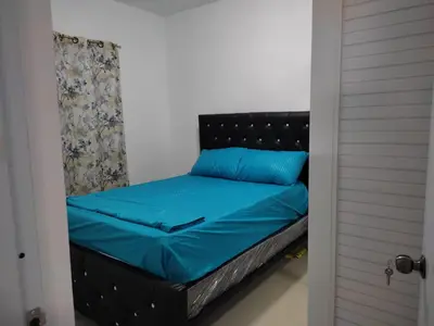 a bed with a black headboard and blue sheets at Residencial Naime 3 Bristol in San Pedro de Macorís