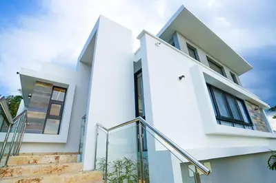 a white house with a staircase in front of it at Modern Villa with a 15m Lap Pool, Cabarete in Cabarete