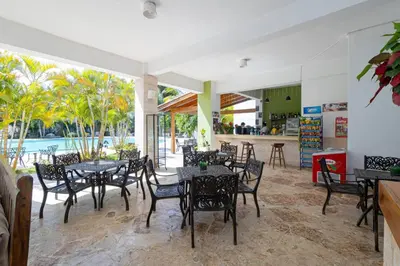 a restaurant with tables and chairs and a pool at Caribbean Escape 1BR at Paraiso Bayahibe in Bayahibe