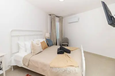 a white bedroom with a white bed with pillows at Caribbean Getaway 2BR at Caribbean Rose Bayahibe in San Rafael del Yuma