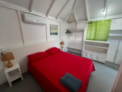 a bedroom with a red bed and green windows at Hostel La Bohème in Las Terrenas