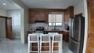 a kitchen with a refrigerator and a table with stools at Cigua Palmera 42 in Puerto Plata
