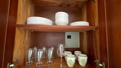 a cabinet with plates and wine glasses on a table at Hideaway Studio - steps from Playa Encuentro at Cabarete in Cabarete