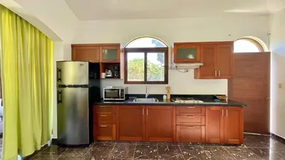 a kitchen with a stainless steel refrigerator and wooden cabinets at Hideaway Studio - steps from Playa Encuentro at Cabarete in Cabarete