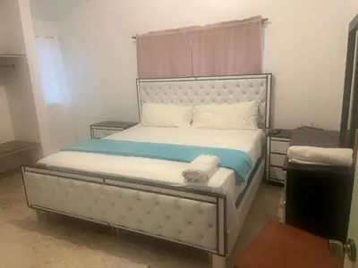 a bedroom with a white bed with a headboard at FredyGreenHouse in Santiago de los Caballeros