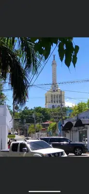 a car parked in a parking lot with a lighthouse in the background at FredyGreenHouse in Santiago de los Caballeros