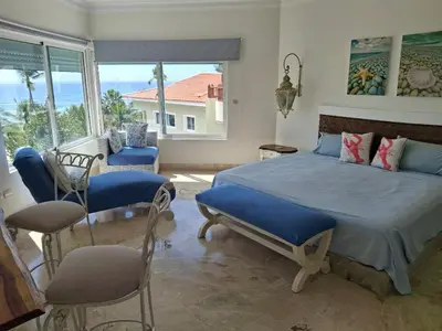 a bedroom with a bed and chairs and a window at Apartment facing the Caribbean Sea, Juan Dolio Beach in Juan Dolio
