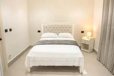 a white bedroom with a large bed and a lamp at Star Villa Boca Chica in Boca Chica