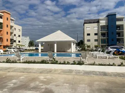 a swimming pool with chairs and a gazebo at Apartmento en Caleta, La Romana in La Romana