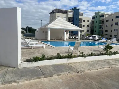 a swimming pool with a gazebo next to a building at Apartmento en Caleta, La Romana in La Romana