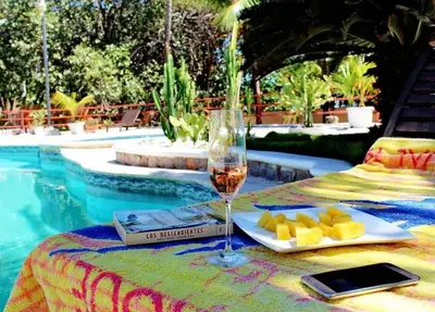 a table with a glass of wine and food next to a pool at Villa can canet in Nizao