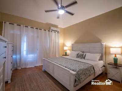a bedroom with a white bed and a ceiling fan at Casa Estrella, Where Relaxation Begins in Sosúa