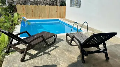 two chairs and a table next to a swimming pool at Villa Turquesa En Dreams House - 5 pax, 2 min de la playa in Las Galeras