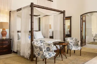 a bedroom with a canopy bed with two chairs and a table at Villa Maji Luxury Private Villa Steps from the Ocean Sea Horse Ranch Cabarete in Cabarete