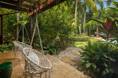 a swing in a garden with palm trees at Villa Maji Luxury Private Villa Steps from the Ocean Sea Horse Ranch Cabarete in Cabarete