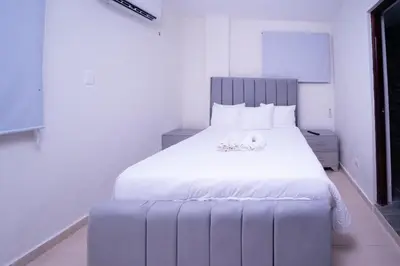 a bedroom with a large white bed with a large headboard at Hotel Porto Escondido in Santa Bárbara de Samaná