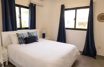 a bedroom with a white bed with blue curtains at Bonita Extravaganza 4 Bedroom, 4 Bed, 3 Bedroom in Sosúa