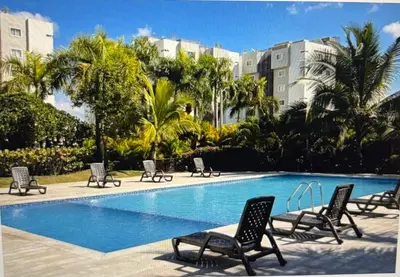 a swimming pool with lounge chairs and palm trees at Residencial Mediterraneo III in Santiago de los Caballeros