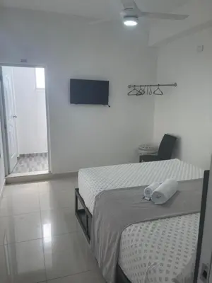a white room with two beds and a television at Plata View Center Habitacion 2D in Monte Plata