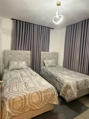 two beds in a bedroom with gray curtains at spectrum stay in Baní