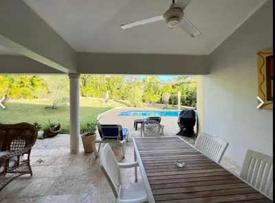 a patio with a wooden table and chairs and a pool at Two residences for one stay in Sosua in Sosúa