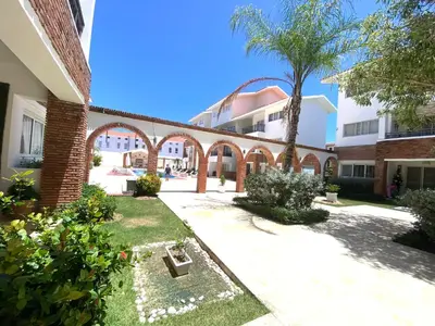 a courtyard of a building with a palm tree at Your Beautiful Village Central 5 Min from the Beach in Punta Cana