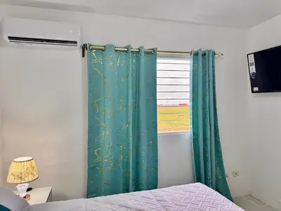 a bedroom with a green curtain and a window at Ocean View Fast Wifi Close to Everything Coffee 2BR in La Cana