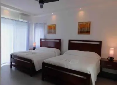 two beds in a bedroom with two lamps and a window at Ocean reset in Sosúa