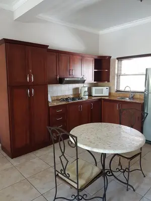 a kitchen with wooden cabinets and a table with chairs at Cozy Garden Oasis Steps to the Beach in Cabarete