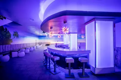 a bar with stools in a room with purple lighting at Majestic Mirage Punta Cana, All Suites – All Inclusive in Punta Cana