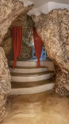 a staircase in a cave with red drapes at La Cueva Eco-Lodge in Las Galeras
