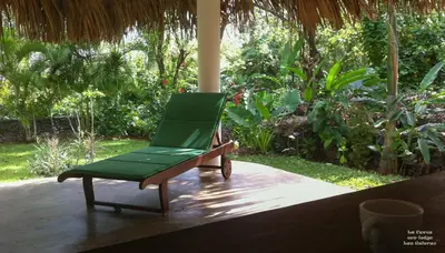 a green chair sitting on top of a porch at La Cueva Eco-Lodge in Las Galeras