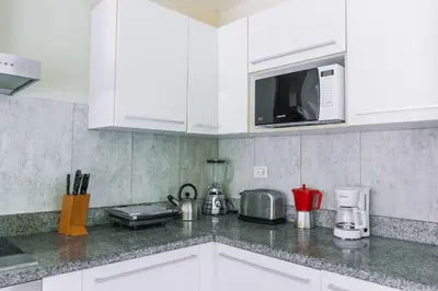a kitchen with white cabinets and a microwave at Luxury Private Villas with Pool, Private Beach, BBQ in Punta Cana