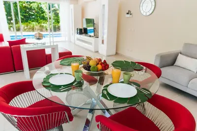 a dining room with a glass table and red chairs at Luxury Private Villas with Pool, Private Beach, BBQ in Punta Cana