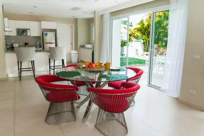 a dining room with a glass table and red chairs at Luxury Private Villas with Pool, Private Beach, BBQ in Punta Cana